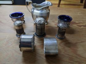 A group of silver items to include a cream jug, two napkin rings, three piece cruet set and a pair
