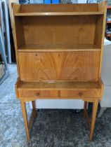 A light wood bureau, open shelves above a fall flap revealing a fitted interior, over two drawers,