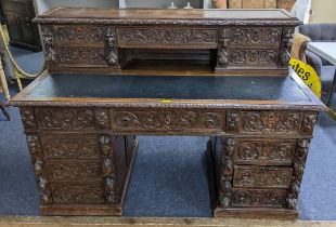 A 19th century heavily carved oak twin pedestal desk having 14 drawers, half leather topped