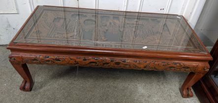A vintage Chinese coffee table having a carved top and border with a glass top, 37cm h x 102cm w