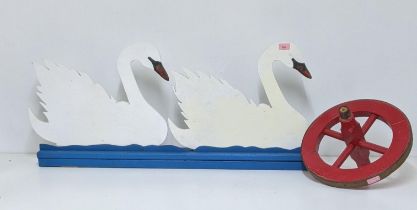 A painted wooden fretwork model of two swans and a painted wheelbarrow wheel Location:G