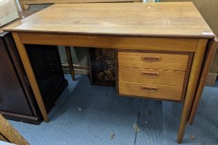 A Scandinavian 1960's teak desk having a single fall flap with three drawers and on turned legs,