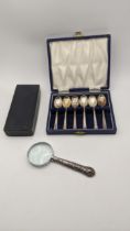 A set of six silver coffee spoons, 55.9g, boxed together with a silver handled magnifying glass