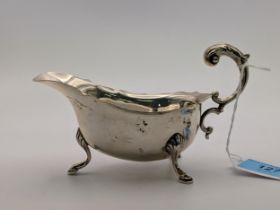 A silver sauce /gravy boat with a 'c' scroll handle, raised on cabriole legs and pad feet,