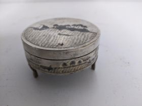 An early 20th century Niello white metal dressing table pot and cover standing on three shaped legs,