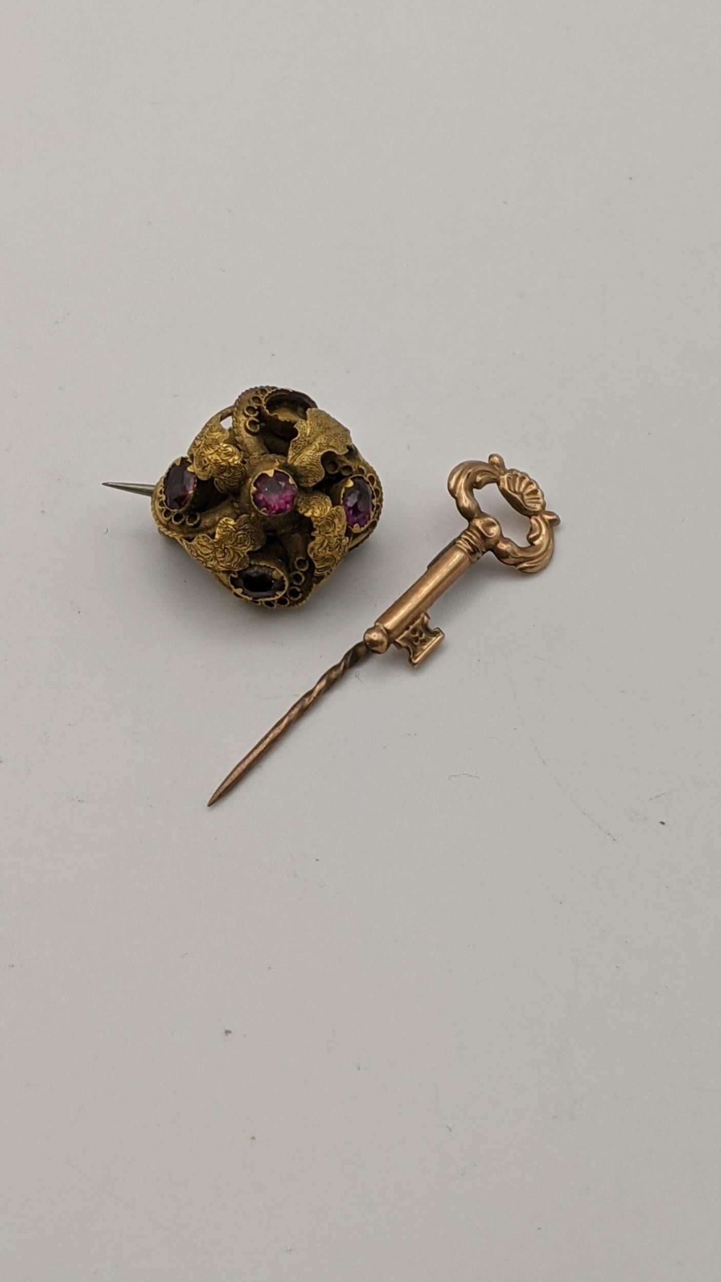 A Victorian yellow metal brooch set with amethyst coloured stones, along with a yellow metal stick