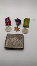 A silver cigarette case with engraved decoration, 114.3g, and a set of three World War II medals