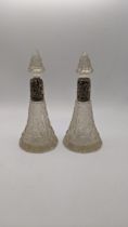 A pair of Victorian silver and crystal cut perfume bottles having floral embossed silver collars