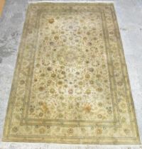 A Persian hand woven pale ground Tabriz rug, having a central flower head motif, surrounded by a