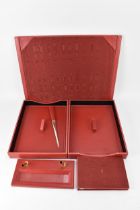 An Asprey & Co red leather desk set consisting of a letter opener, pen holder, notepad, blotter
