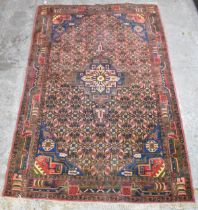 A North West Iran Nahavand hand woven rug, having a red ground with a central medallion surrounded