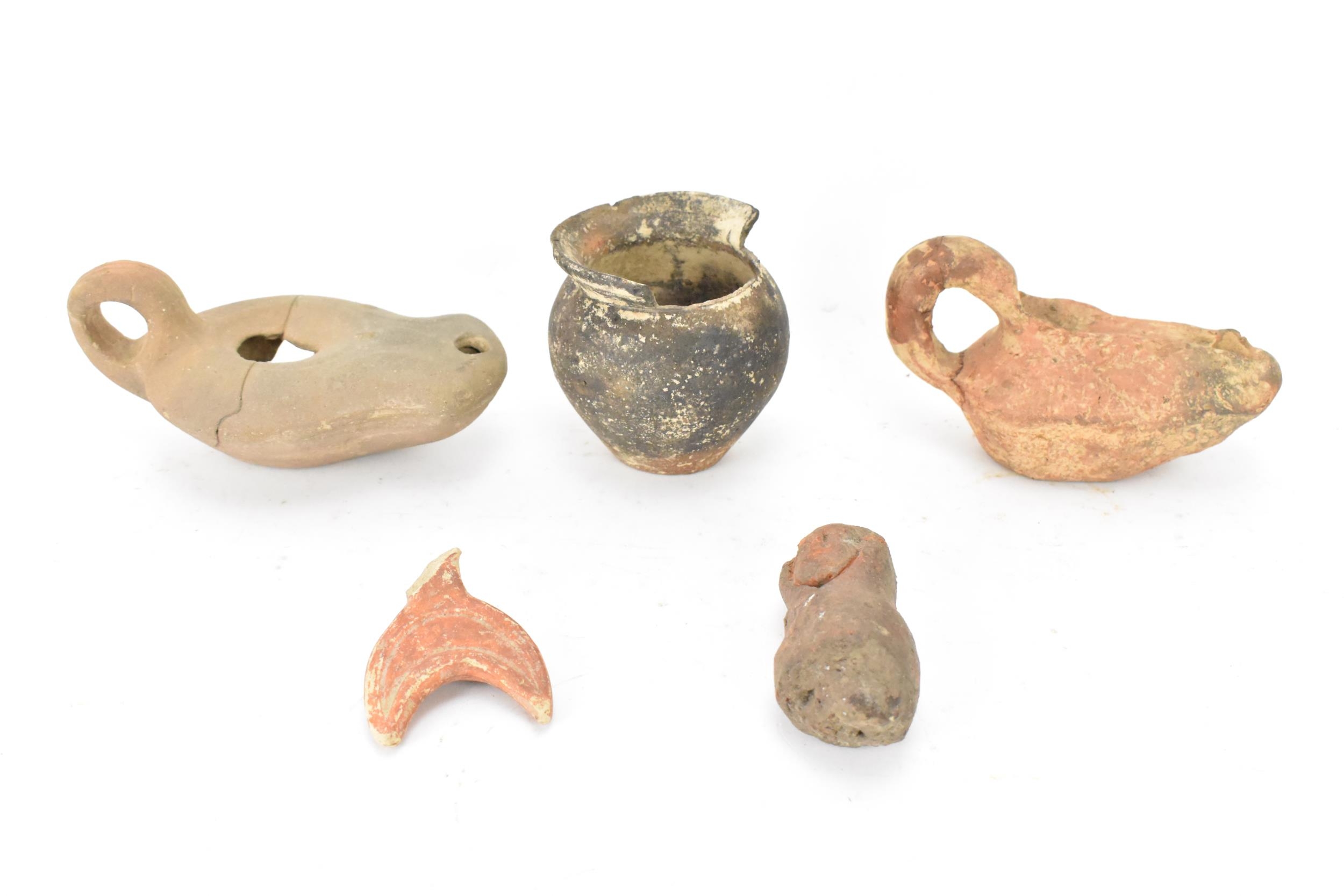 A collection of Roman pottery to include two terracotta oil lamps, a pot, a crescent shaped handle
