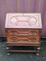 An early 20th century oak bureau having a fall flap above two drawers, on bulbous supports,