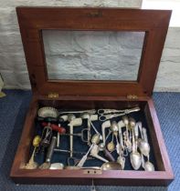 An Edwardian mahogany display box containing carved pipes, silver and silver plated cutlery and