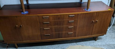 A mid century teak bow fronted sideboard, four graduating central drawers flanked by two sets of