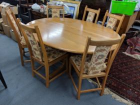 A blonde Ercol oval dining table on a quadruped base with six Ercol dining chairs with upholstered