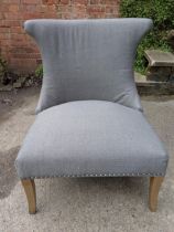 A modern grey fabric upholstered low chair with a chrome ring handle to the back, on square legs,