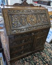 A 19th century pussy oak carved bureau having a raised top, fitted interior with drawers and