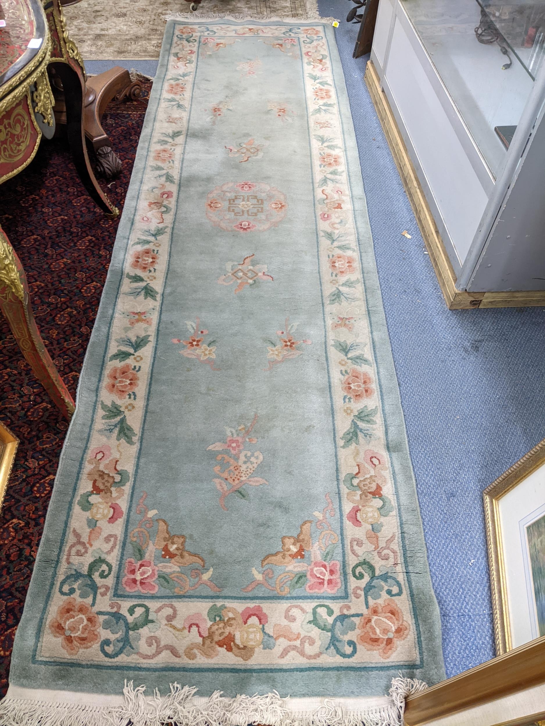 A Chinese floral patterned runner on a light blue and cream ground 321cm x 86cm Location: