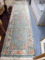 A Chinese floral patterned runner on a light blue and cream ground 321cm x 86cm Location: