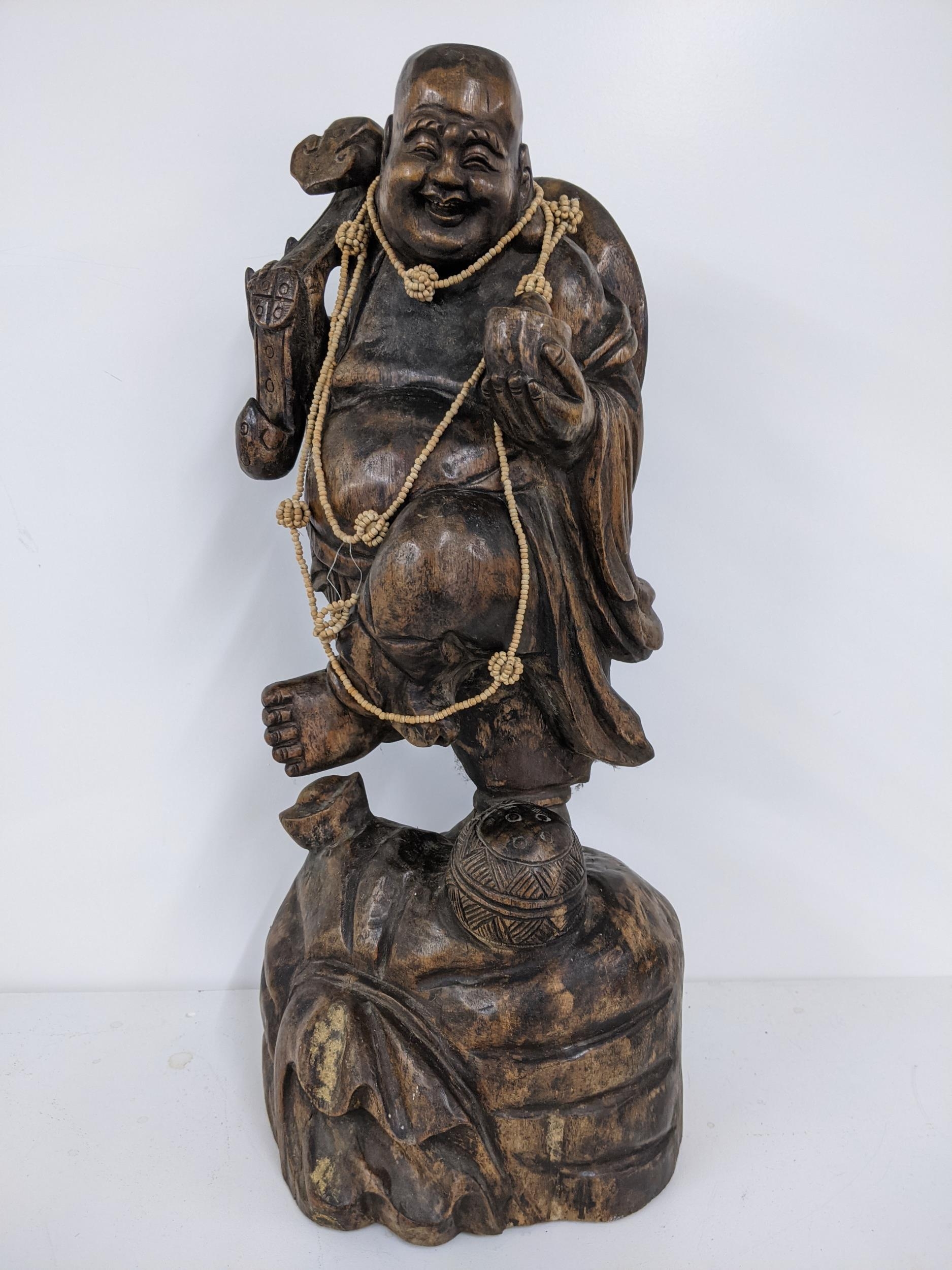 A Chinse treen carved figure of a smiling Buddha, holding a staff to one hand, 57.5h, Location: - Image 2 of 4