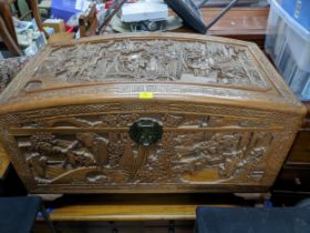 A Chinse camphor wood carved chest, domed top with a relief carved landscape panel of figures in