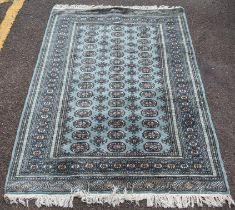 A Pakistani hand woven green ground rug having elephant foot motifs within multiguard borders, 190cm