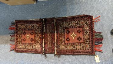 A Persian saddle bag rug having geometric motifs on a red ground 49cm w x 125cm l Location:
