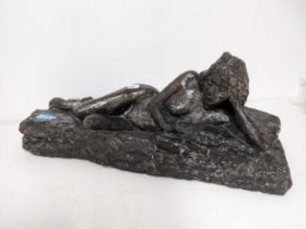 A coloured plaster slip cast sculpture of a reclining nude woman reading a book, 50cm long x 21cm