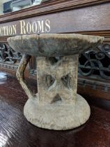 An African Tonga stool with a carrying handle and a flat seat, two decorated supporting columns on a