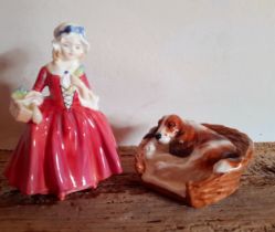 Two Royal Doulton bone china ornaments comprising a model of a hound in a basket HN2586 and a figure