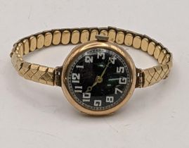 A 9ct gold ladies wristwatch with a black dial on a later plated expandable bracelet Location: