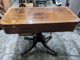 An early Victorian mahogany and crossbanded veneered fold over tea table on turned and fluted column