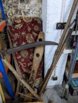 A group of vintage wooden handled garden and farm tools to include a scythe, and a horse's neck yoke