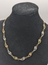 A 9ct gold yellow and white gold necklace with tear drop design links and inset with paste stones,