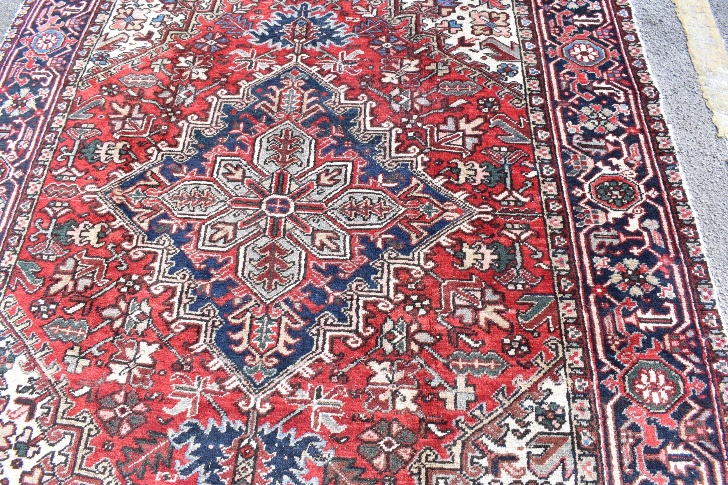 A Persian Heriz hand woven rug, having a red ground with a central motif within a field of - Image 7 of 8