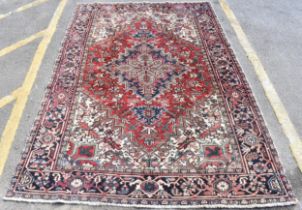 A Persian Heriz hand woven rug, having a red ground with a central motif within a field of