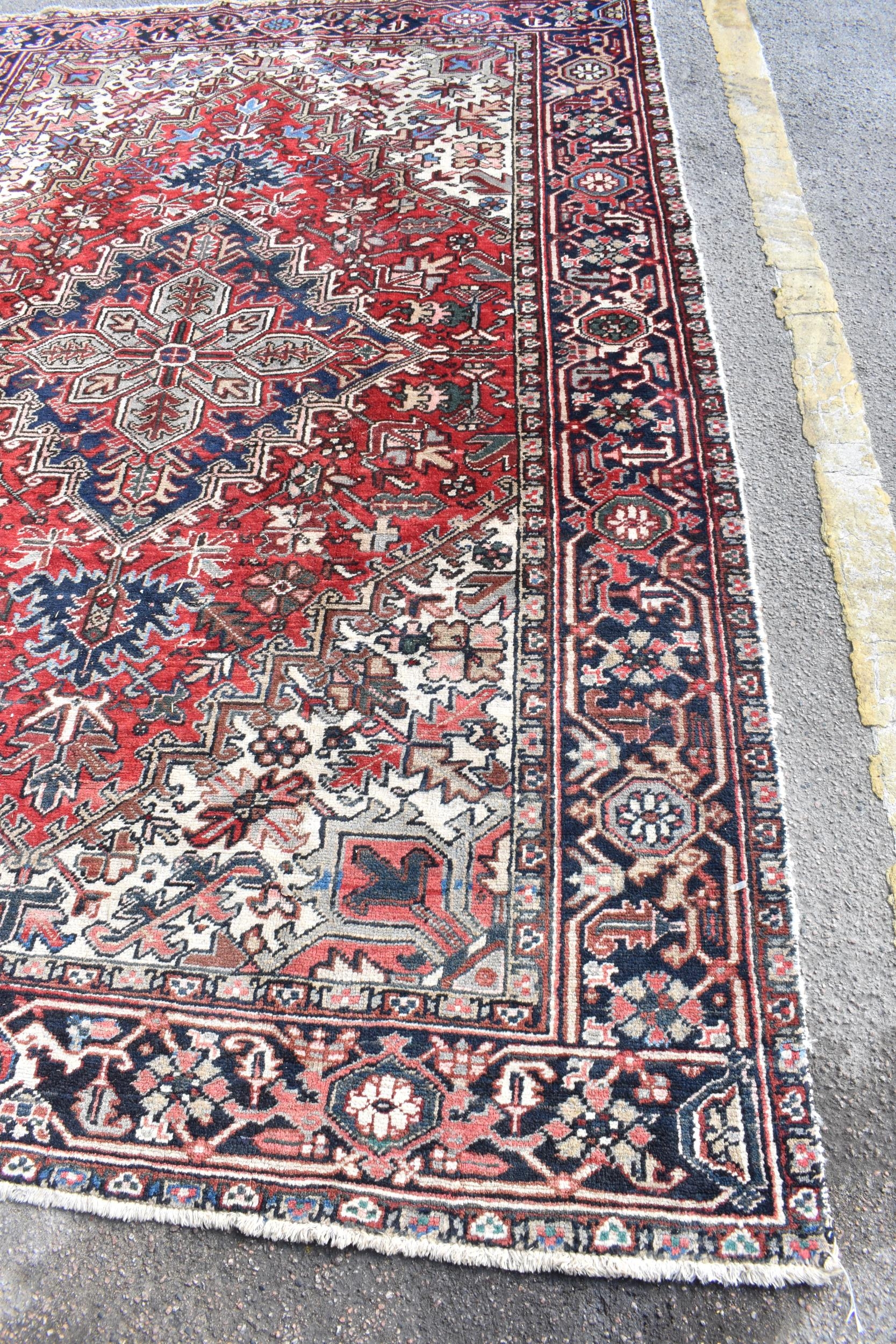 A Persian Heriz hand woven rug, having a red ground with a central motif within a field of - Image 2 of 8