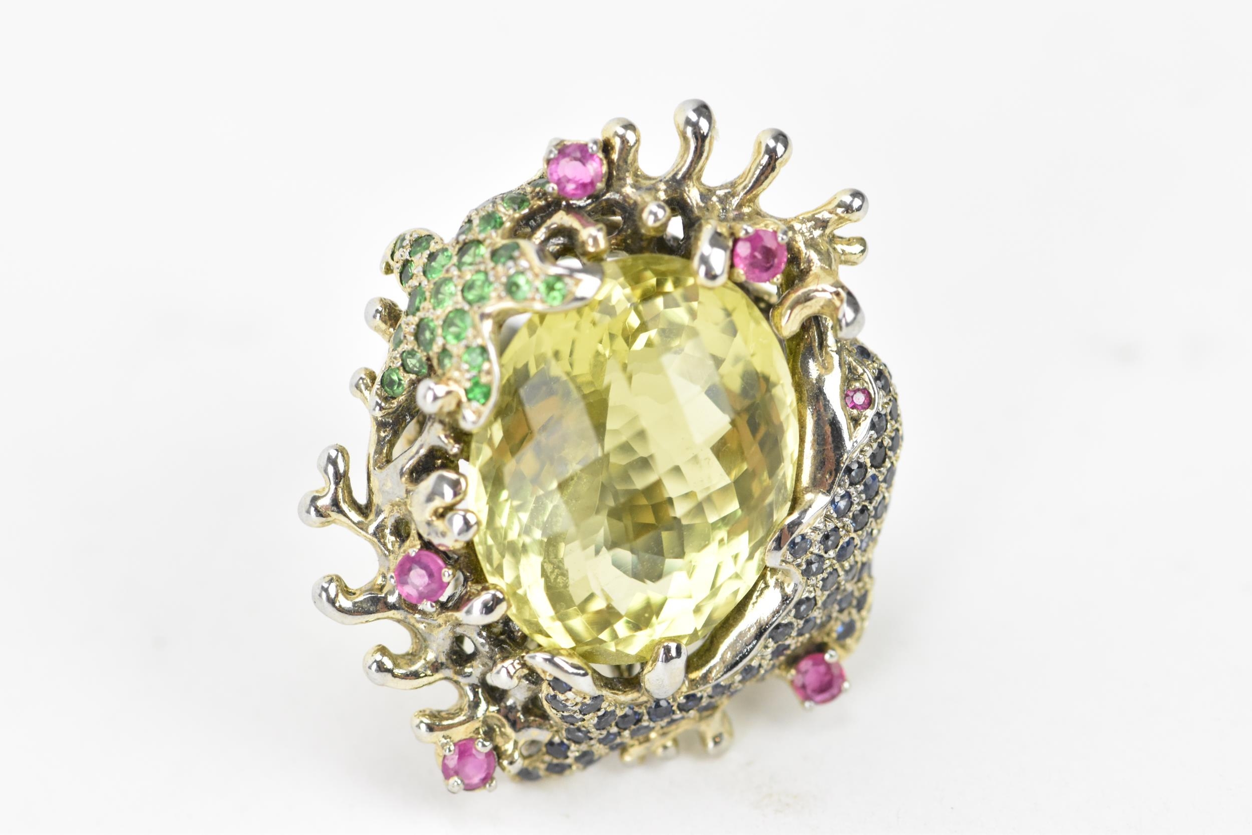A silver dress ring inset with a large lemon quartz to the centre, decorated with a dolphin and