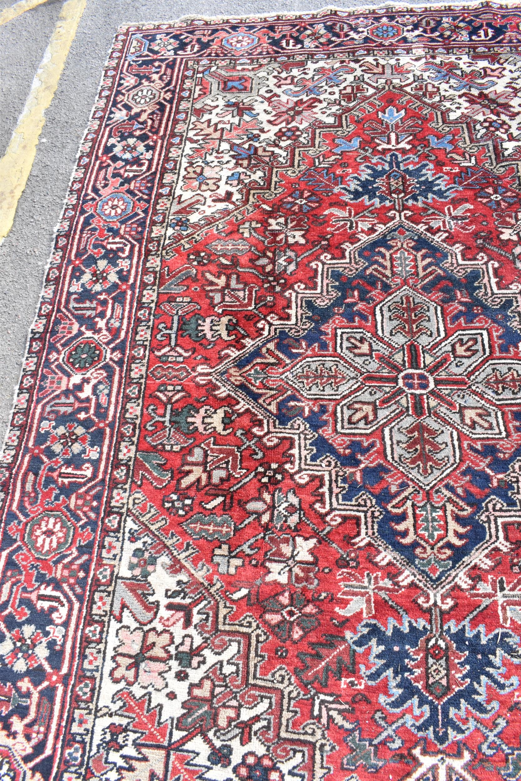 A Persian Heriz hand woven rug, having a red ground with a central motif within a field of - Image 4 of 8