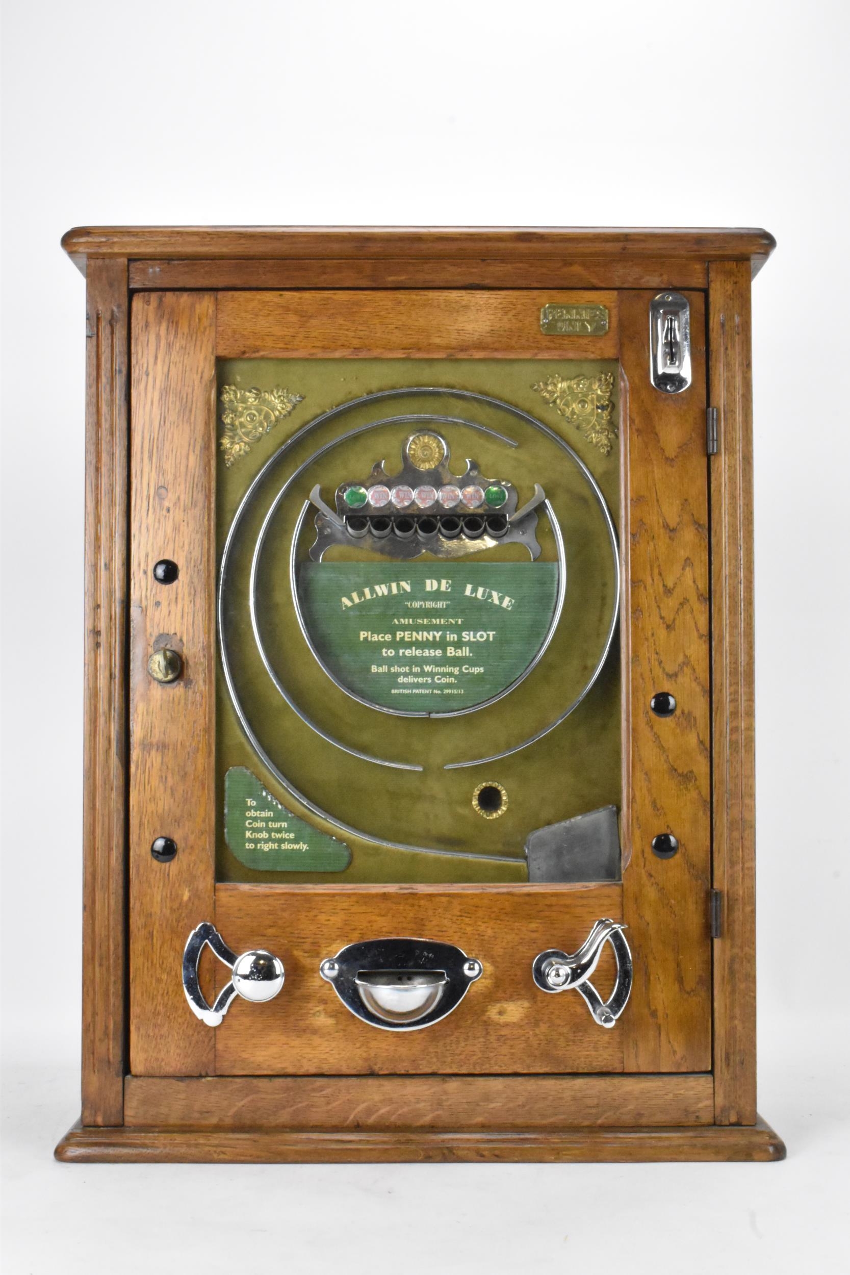 An Allwin De Luxe oak cased penny slot machine, circa 1920, with internal metal ball track,