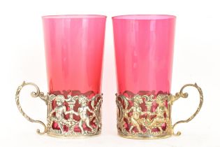 A pair of Edwardian silver glass holders with a pair of cranberry glasses, the holders ornately