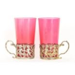 A pair of Edwardian silver glass holders with a pair of cranberry glasses, the holders ornately