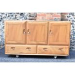 A mid 20th century Ercol Windsor range light elm sideboard, mode 468, having three cupboard doors