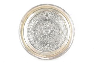 A South American white metal dish having a raised edge and embossed decoration bearing the Aztec