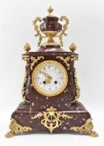 A late 19th century French red marble mantle clock, the case having gilt metal mounts with urn