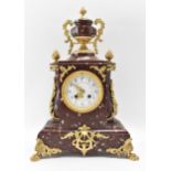 A late 19th century French red marble mantle clock, the case having gilt metal mounts with urn