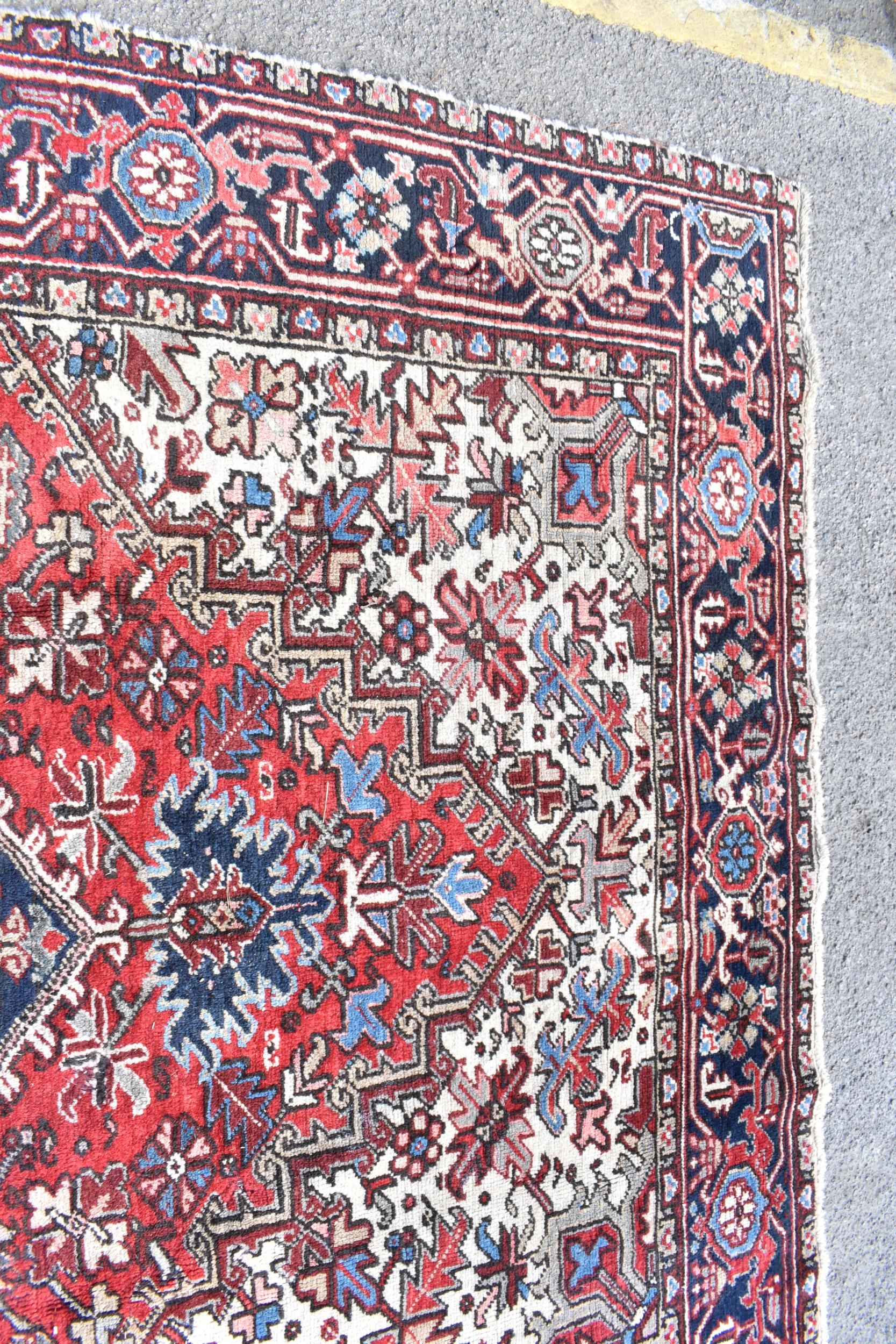 A Persian Heriz hand woven rug, having a red ground with a central motif within a field of - Image 5 of 8