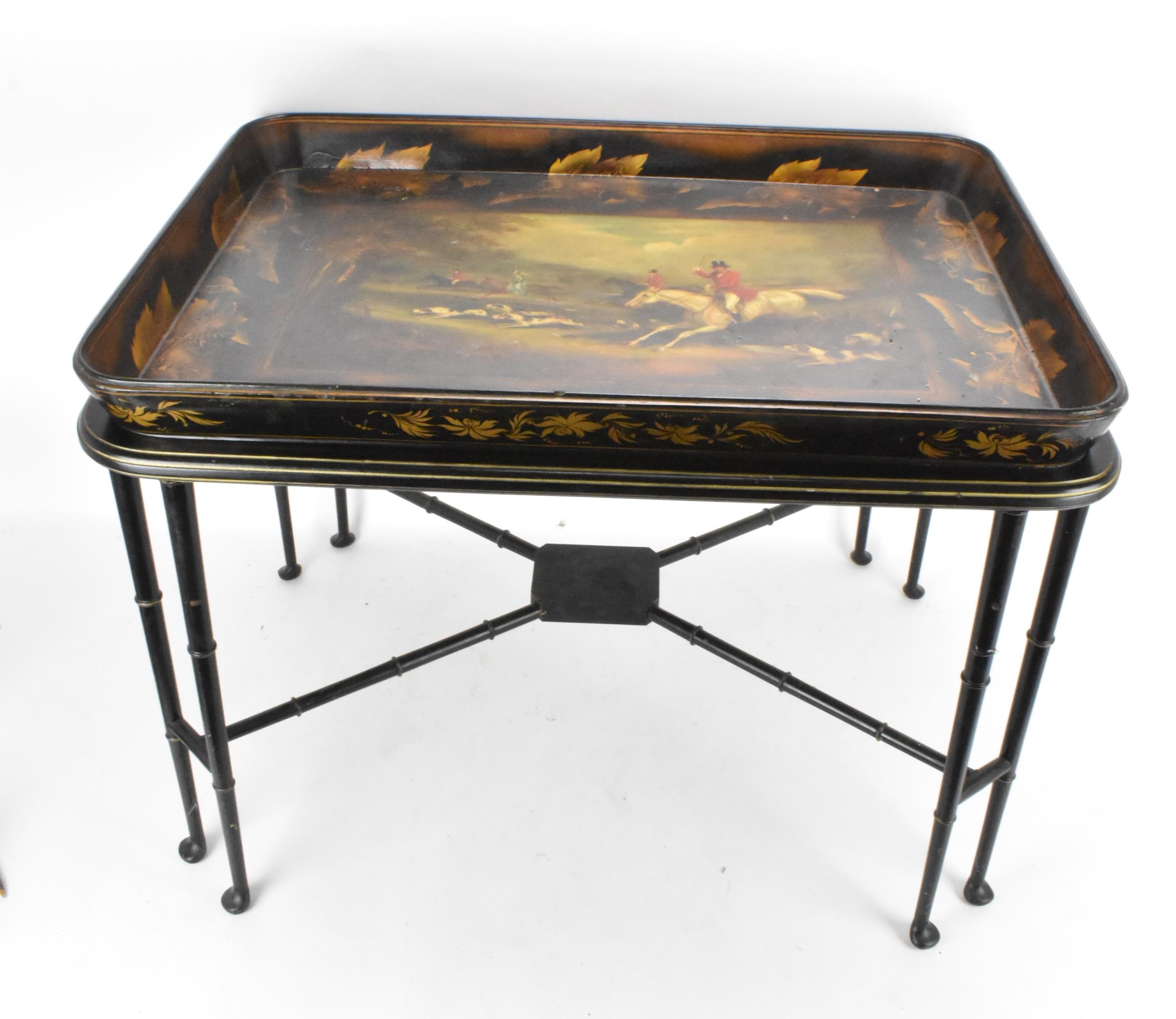 A tray top table having a Victorian black lacquered papier mache tray with a floral border enclosing