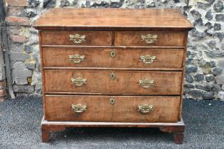 A circa 1700 walnut chest of drawers, having a quarter cut veneered and cross banded top, two